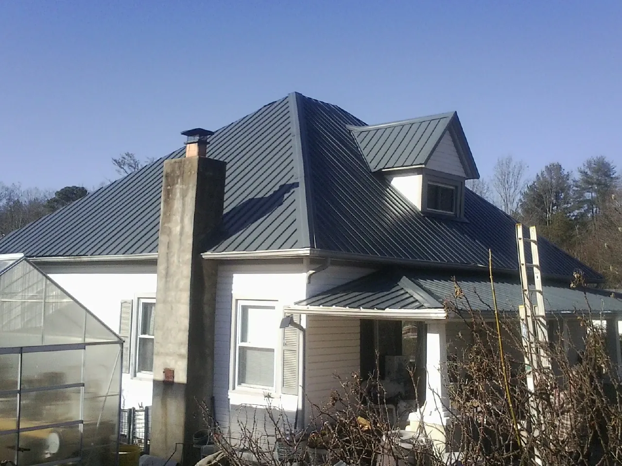 Dark blue standing seam metal roof on a white farmhouse with dormer — Slate & Tile Roof Repair by Roofing Brothers in Ruffs Dale