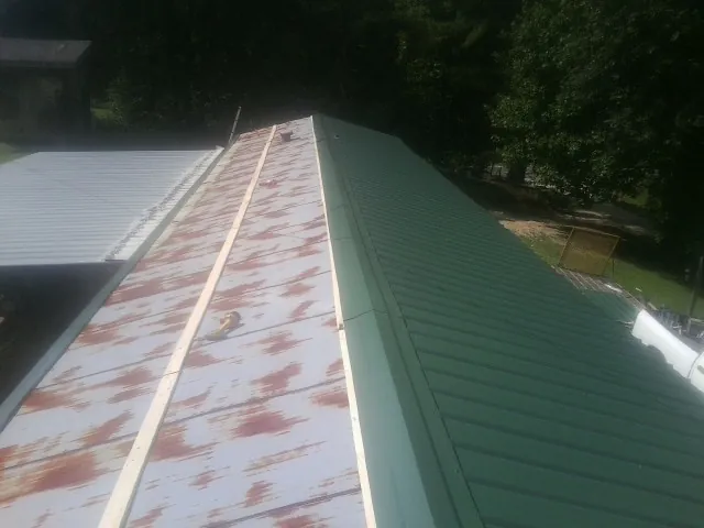 Old rusted panels beside newly installed green metal roofing — Wind Damage Roof Repair by Roofing Brothers in Ruffs Dale