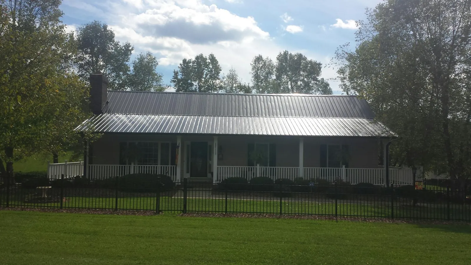 Gray metal roof on a brick ranch with a full width front porch — Gutter Guard Installation work by our crew in Ruffs Dale
