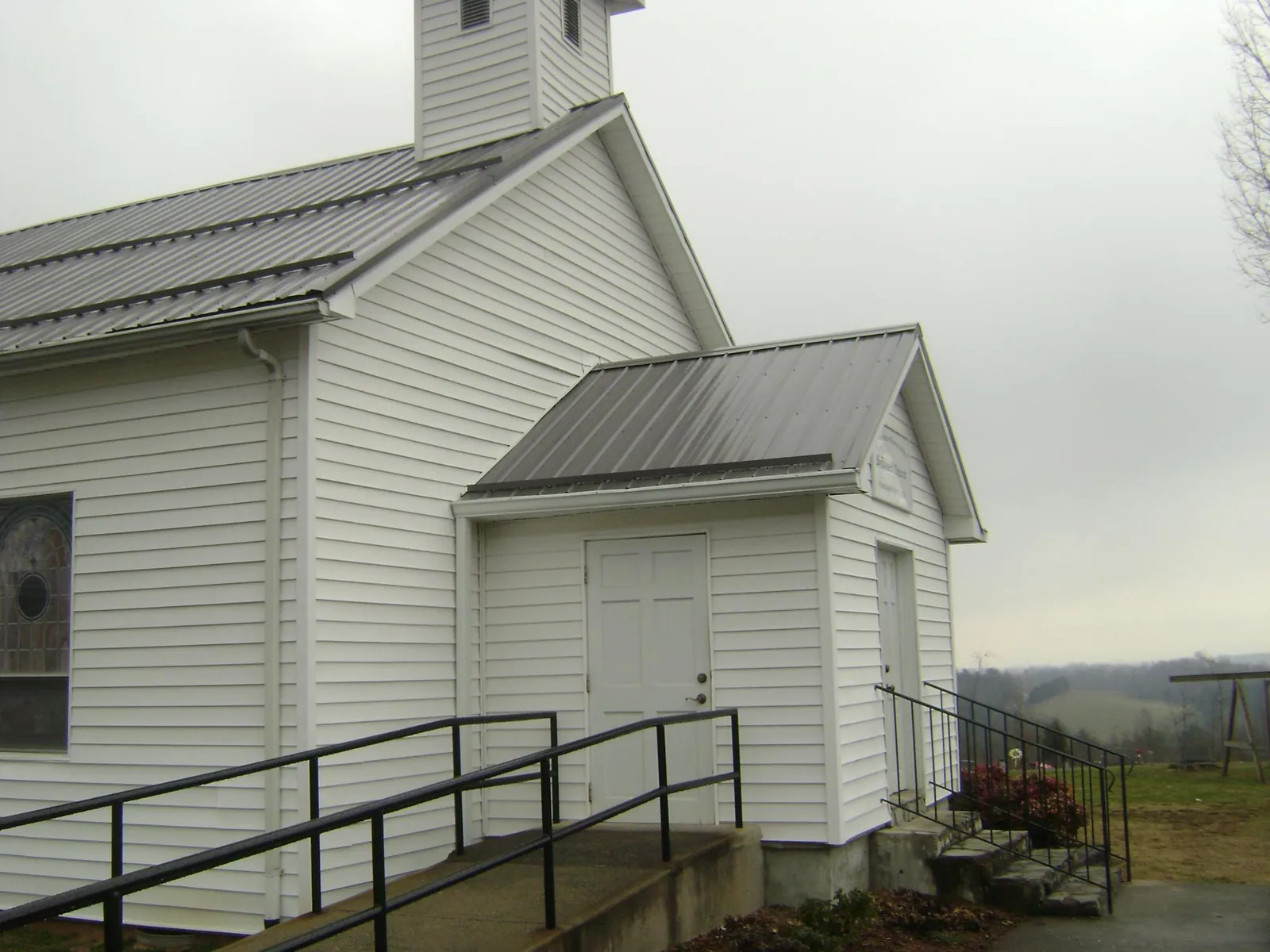 Gray metal roof on a white clapboard church with a steeple in Ruffs Dale